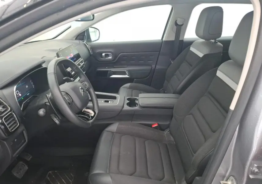 Vue intérieure côté conducteur du Citroën C5 Aircross gris Artense, sièges tissu noir avec surpiqûres grises et console centrale.