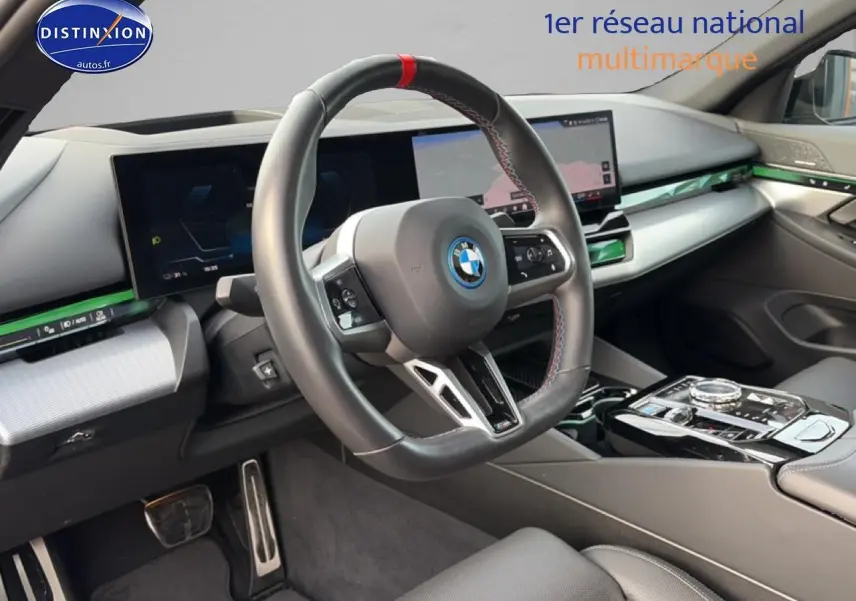 Intérieur BMW Série 5 i5 M60 2024 vu côté conducteur, volant sport cuir avec surpiqûres tricolores et tableau de bord digital.