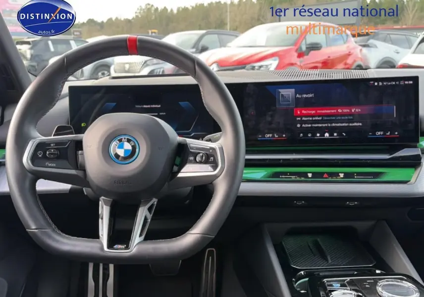 Vue intérieure centrée sur le volant cuir noir et l'écran tactile large du tableau de bord d'une BMW Série 5 i5 M60.