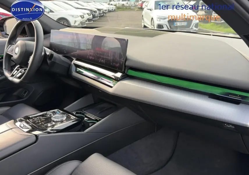 Vue intérieure côté passager de la BMW Série 5 i5 M60 noire 2024 avec tableau de bord moderne et écran tactile large.