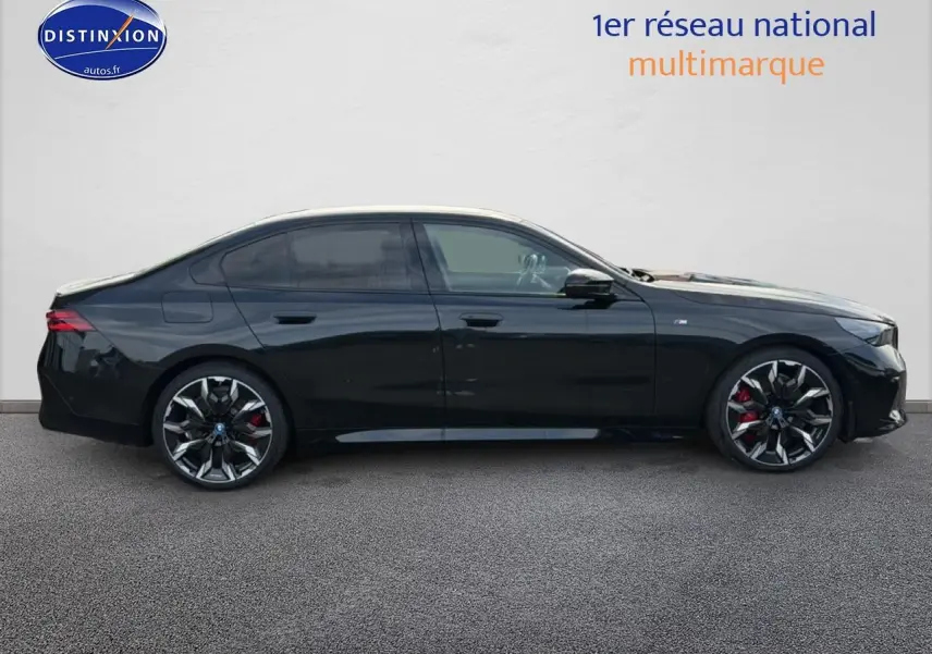BMW Série 5 i5 M60 noir vue de profil côté gauche, avec jantes alu bicolores et étriers rouges visibles.