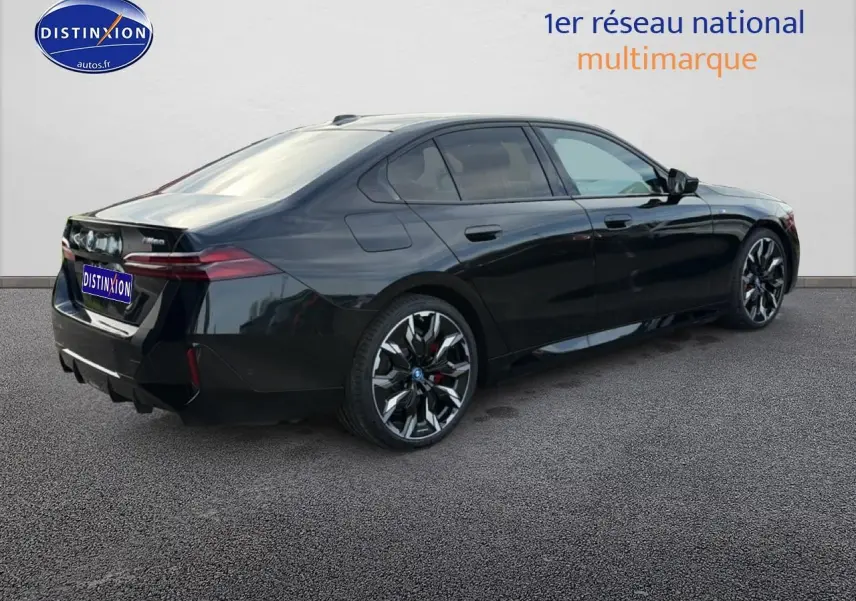 BMW Série 5 i5 M60 noire vue en 3/4 arrière droit, avec jantes alu bicolores et feux arrière LED distinctifs.