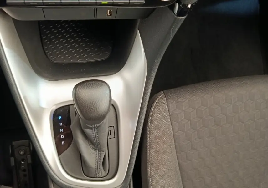 Vue intérieure centrée sur la console centrale et levier de vitesse automatique de la Toyota Yaris hybride 2022, sièges gris.