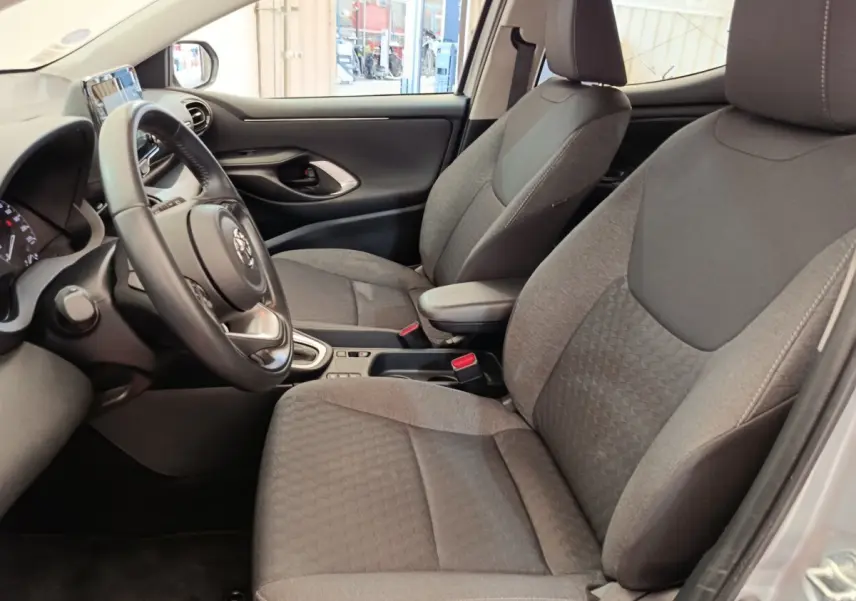 Intérieur avant gris clair de la Toyota Yaris Hybride 2022, vue côté conducteur avec volant cuir multifonctions.