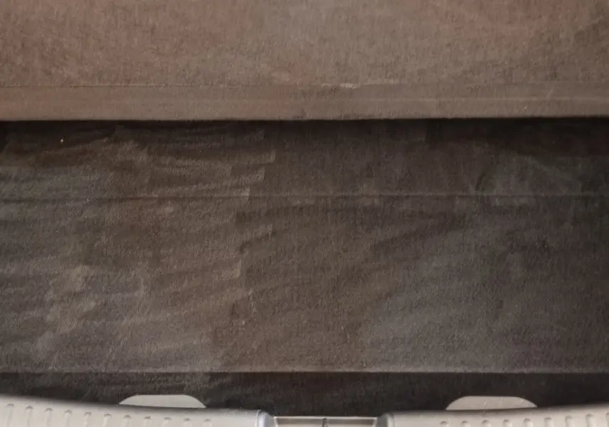 Vue plongeante sur le coffre gris clair de la Toyota Yaris hybride 2022, montrant la moquette et la tablette arrière.