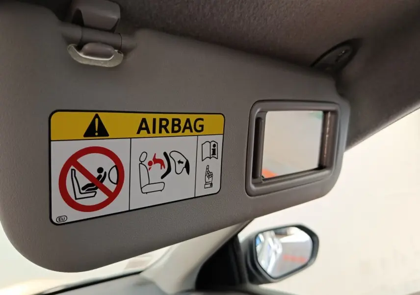 Détail du pare-soleil côté conducteur gris clair avec miroir et avertissement airbag dans une Toyota Yaris hybride 2022.