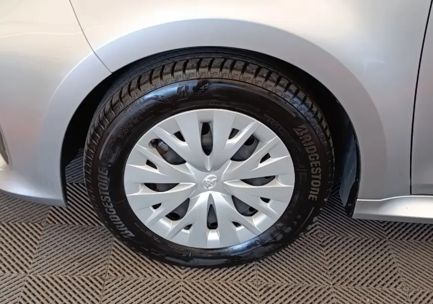 Gros plan sur la roue avant droite grise claire d'une Toyota Yaris hybride avec enjoliveur et pneu Bridgestone.