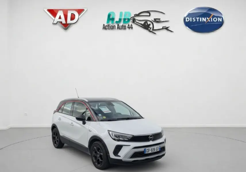 Opel Crossland X blanc 3/4 avant droit avec toit noir et jantes noires dans un studio blanc.