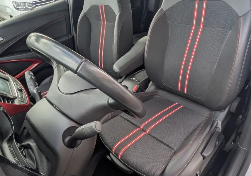 Vue intérieure côté conducteur de l’Opel Crossland X 2021 avec sièges noirs à bandes rouges et volant cuir.