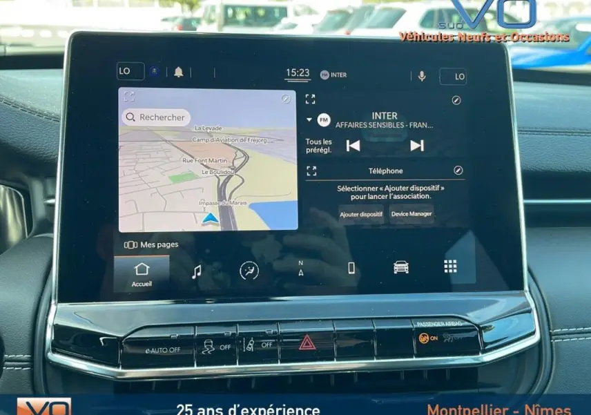 Écran tactile central du Jeep Compass 2023 affichant navigation et radio, avec tableau de bord noir en arrière-plan.