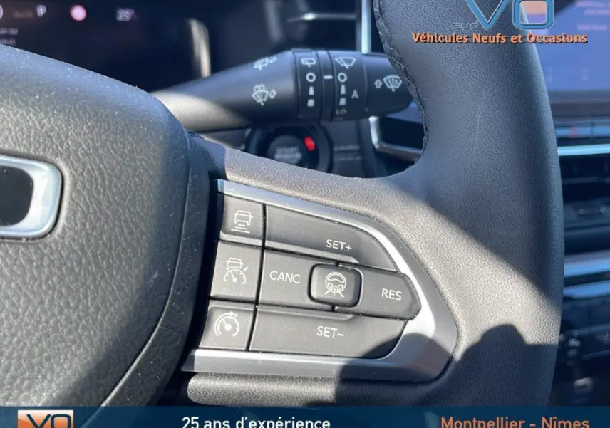Gros plan sur les commandes au volant du Jeep Compass 2023 noir, mettant en valeur les boutons du régulateur de vitesse.