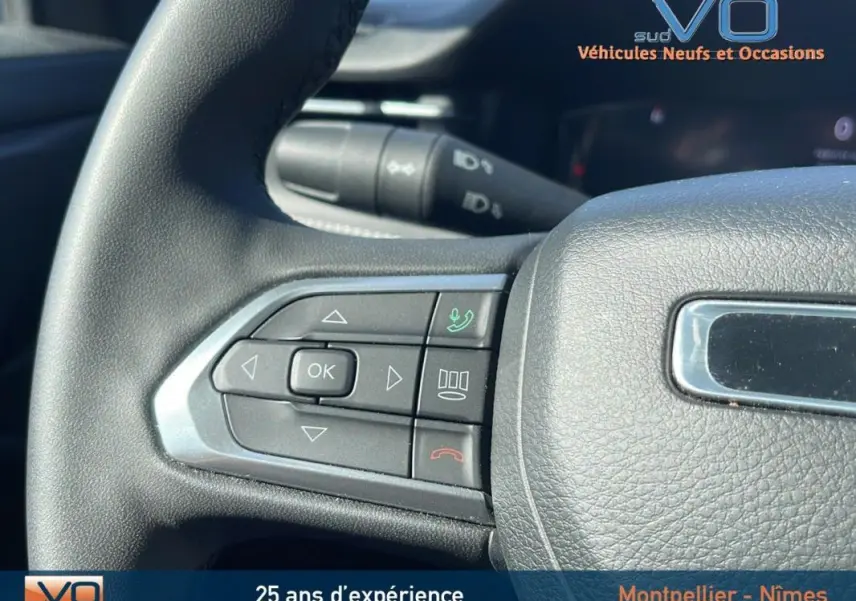 Gros plan sur les commandes gauche du volant du Jeep Compass noir 2023, avec boutons de navigation et appel.
