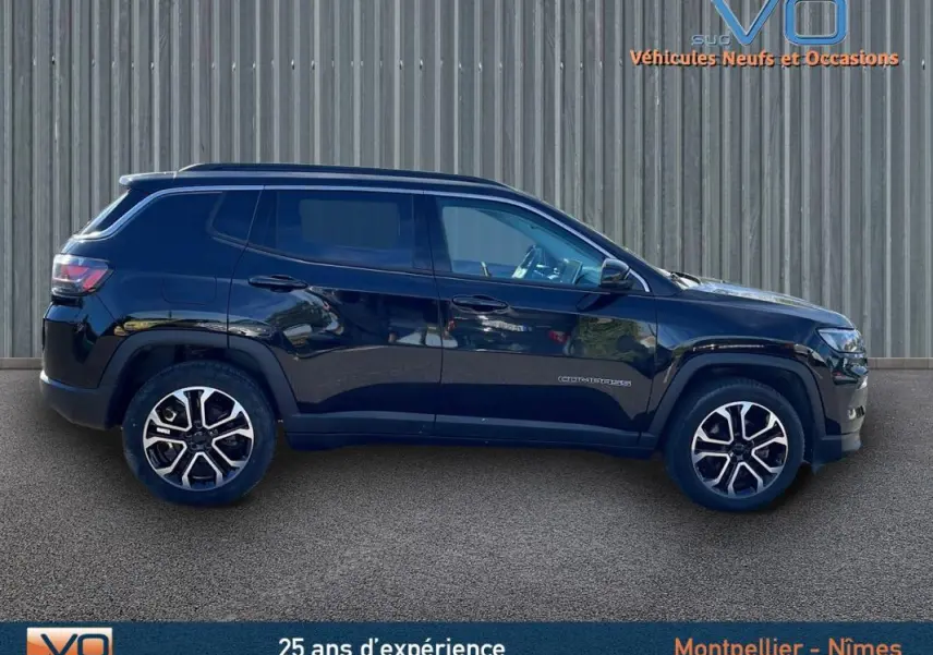 Profil côté gauche d'un Jeep Compass noir 2023 avec jantes 18 pouces et barres de toit visibles sur fond urbain.