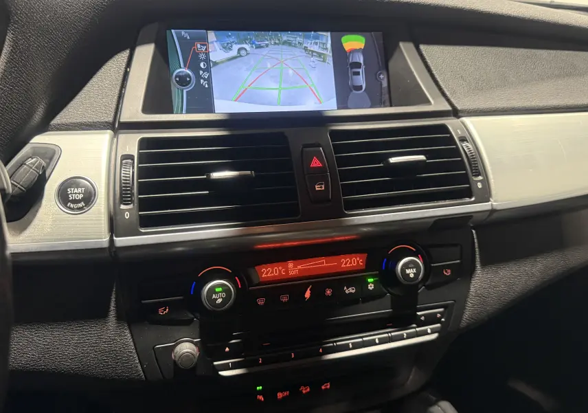 Vue rapprochée de la console centrale du BMW X6 2026 avec écran de caméra de recul et commandes de climatisation.