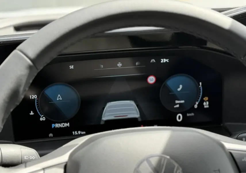 Vue rapprochée du tableau de bord numérique du Volkswagen Transporter T7 gris argent, affichant la vitesse et les aides à la conduite.