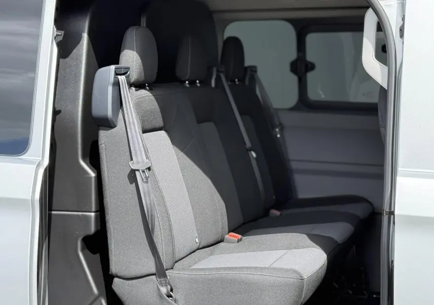 Vue intérieure côté gauche du Volkswagen Transporter T7 ProCab gris argent, montrant la banquette arrière en tissu gris.