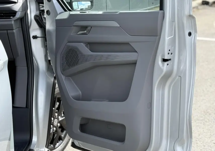 Vue rapprochée de la porte avant gauche gris argent du Volkswagen Transporter T7 avec jante alliage noir brillant visible.