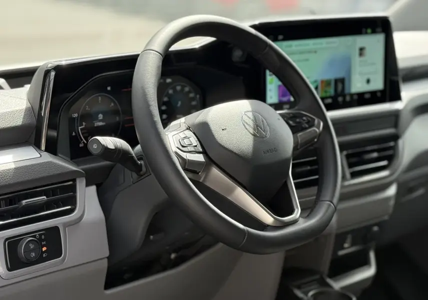 Vue rapprochée du volant multifonction noir et du tableau de bord digital du Volkswagen Transporter T7 2026.