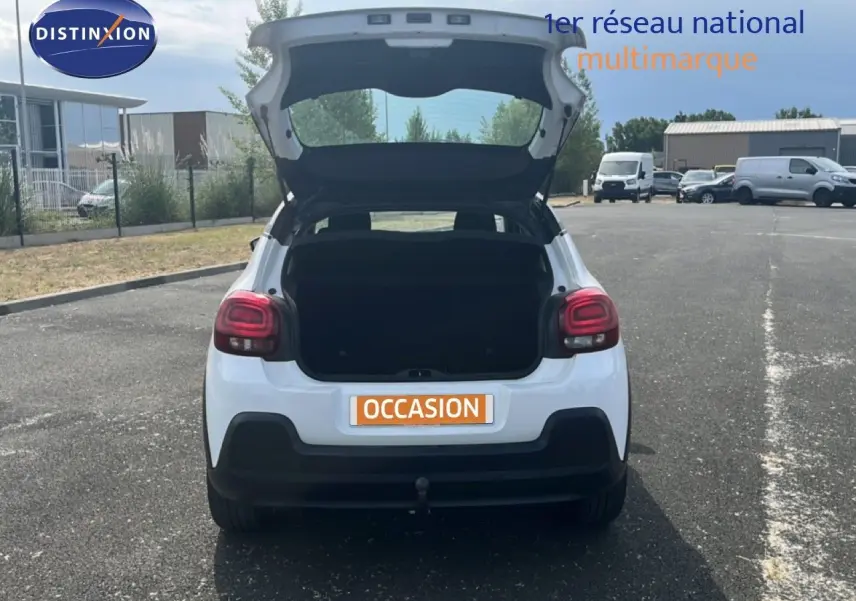 Vue arrière d'une Citroën C3 blanche de 2018 avec coffre ouvert sur un parking extérieur.