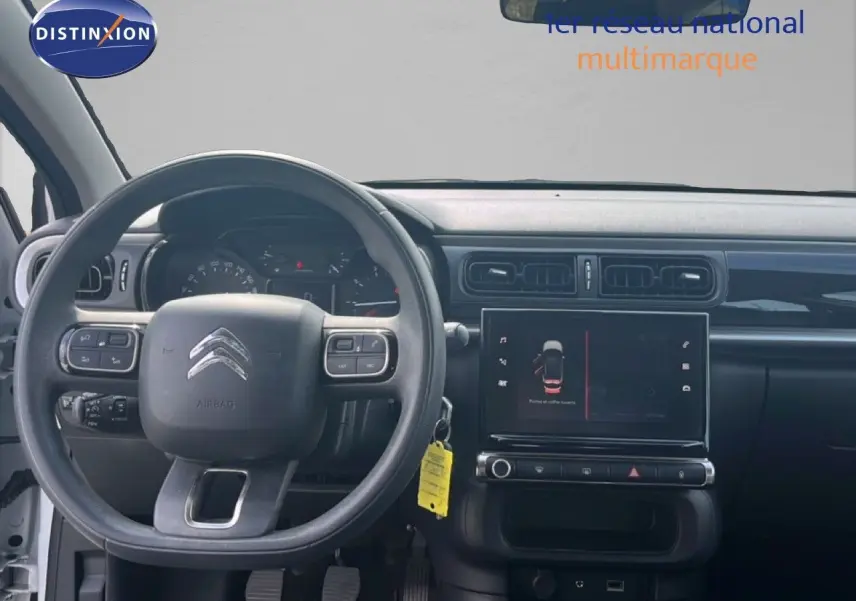 Vue intérieure frontale du tableau de bord noir et volant Citroën C3 blanc 2018 avec écran tactile central allumé.