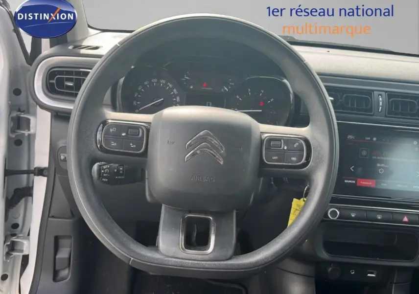 Vue intérieure centrée sur le volant noir d'une Citroën C3 blanche de 2018 avec tableau de bord et écran tactile.