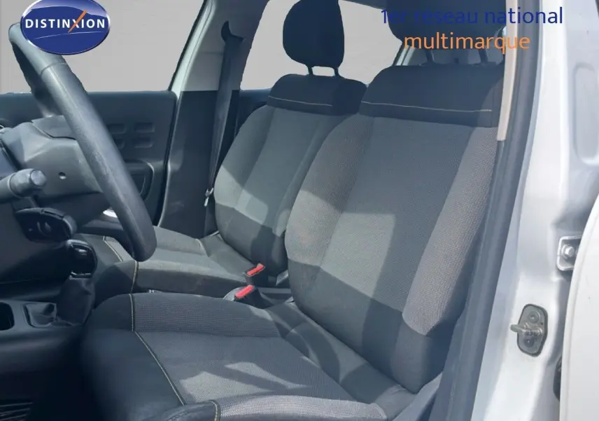 Vue intérieure côté conducteur d'une Citroën C3 blanche 2018, sièges en tissu gris avec coutures contrastantes.