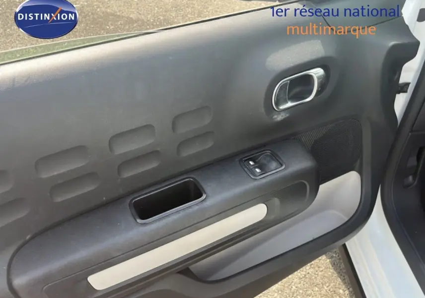 Vue rapprochée de la porte avant droite blanche d'une Citroën C3 2018, avec commande de fenêtre électrique et poignée chrome.