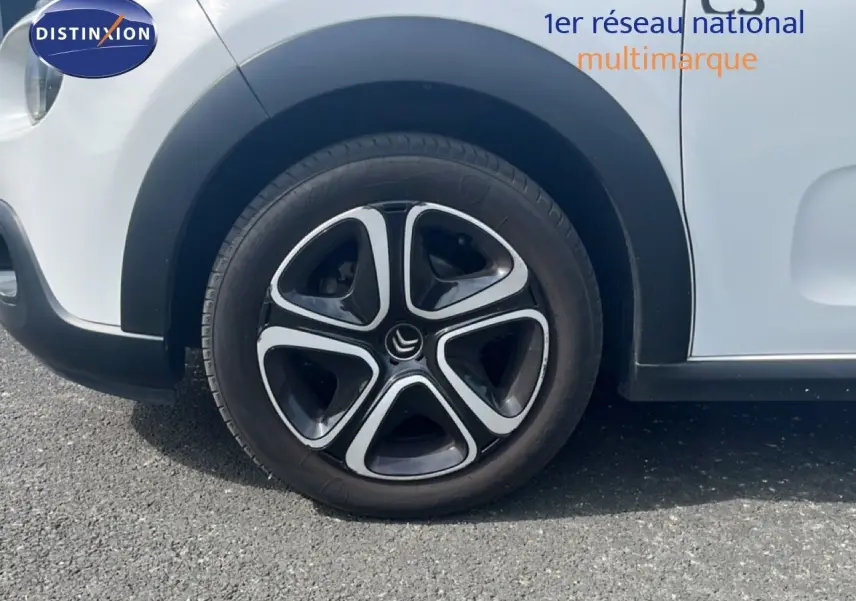 Gros plan sur la roue avant gauche d'une Citroën C3 blanche de 2018 avec jante alliage noire et argentée.