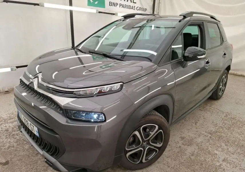 Citroën C3 Aircross gris foncé en 3/4 avant droit avec barres de toit noires et jantes 16 pouces.