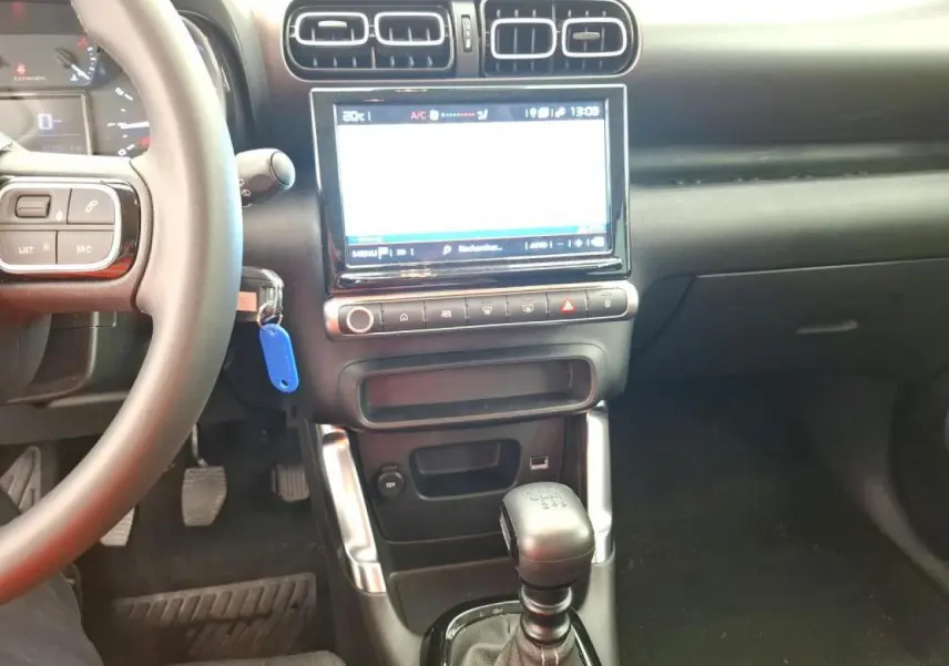 Vue intérieure centrée sur la console centrale et levier de vitesses manuelle du Citroën C3 Aircross 2023 gris foncé.