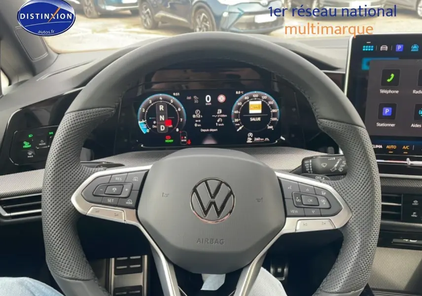 Vue intérieure centrée sur le volant noir perforé de la Volkswagen Golf 2026 avec tableau de bord numérique et écran tactile.