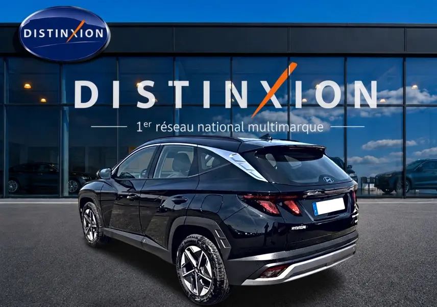 Vue 3/4 arrière droite d’un Hyundai Tucson noir 2026 garé devant une vitrine avec logo Distinxion.
