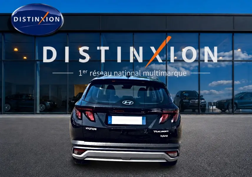 Vue arrière d'un Hyundai Tucson noir hybride garé devant une vitrine avec logo Distinxion.