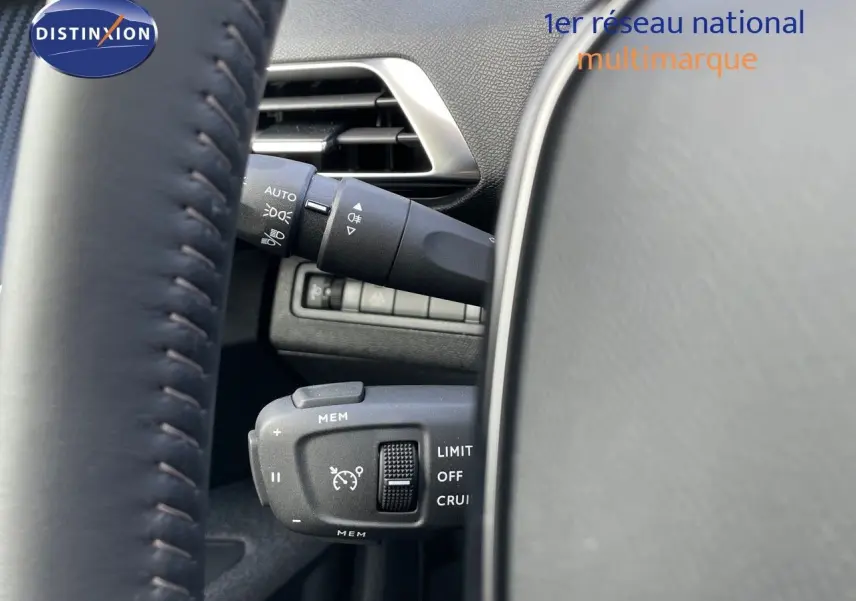 Gros plan sur les commandes de régulateur de vitesse et éclairage à gauche du volant d'un Peugeot 3008 bleu Célebès Métal.
