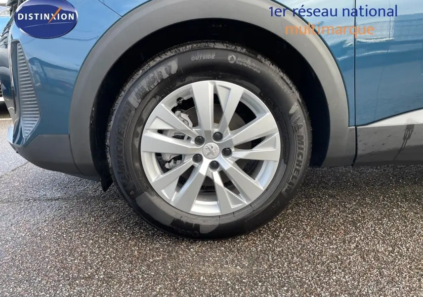 Gros plan sur la roue avant gauche d'un Peugeot 3008 bleu Célèbes Métal avec jante alliage argentée.