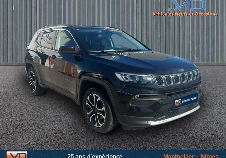 Jeep Compass noir en 3/4 avant droit, avec barres de toit et jantes 18 pouces visibles sur fond urbain.
