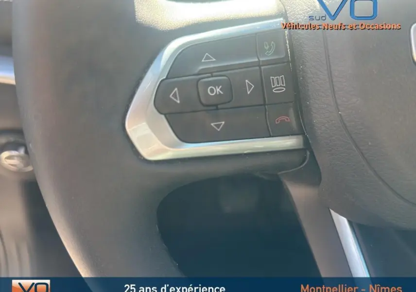 Gros plan sur les commandes au volant du Jeep Compass noir 2023, mettant en valeur les boutons multifonctions.