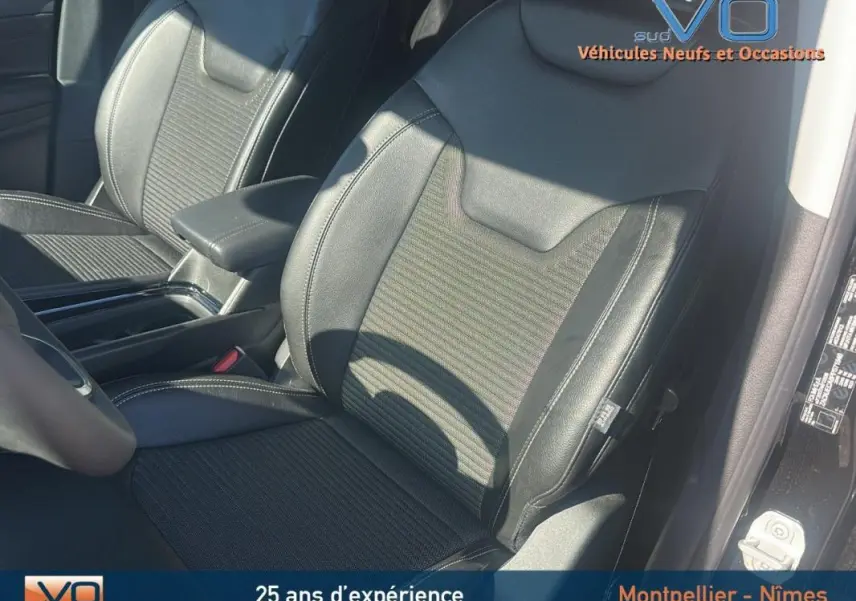 Gros plan sur les sièges avant noirs en cuir et tissu du Jeep Compass 2023 avec accoudoir central visible.