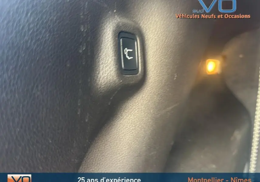 Bouton d'ouverture du hayon intérieur sur un Jeep Compass noir 2023, vue rapprochée du coffre.