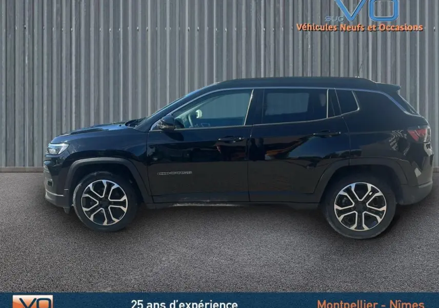 Profil côté gauche d'un Jeep Compass noir 2023 avec jantes 18 pouces, barres de toit et rétroviseurs électriques rabattables.