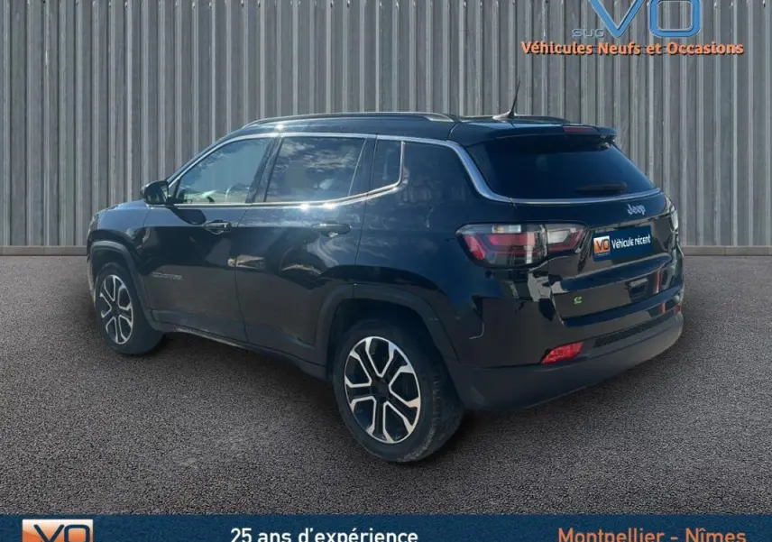 Jeep Compass noir en 3/4 arrière côté gauche, avec barres de toit et jantes 18 pouces visibles.