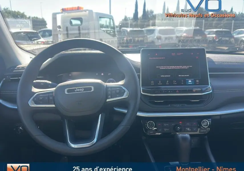 Vue intérieure frontale du tableau de bord et volant noir du Jeep Compass 2023 avec écran tactile et commandes intégrées.