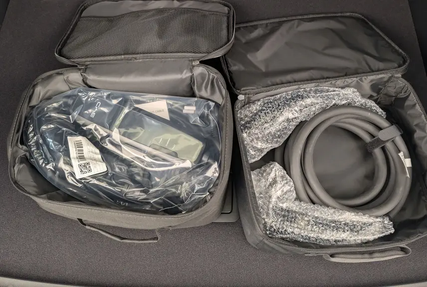 Gros plan sur les câbles de recharge dans des sacs noirs ouverts, posés dans le coffre d’un BYD SEAL U Obsidian Black.