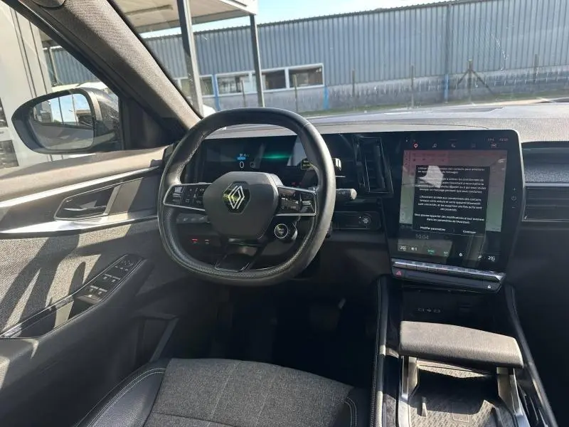 Vue intérieure côté conducteur du Renault Espace 2024, tableau de bord moderne avec écran tactile vertical et volant multifonction.