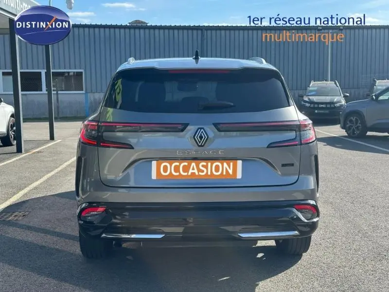 Vue arrière d'un Renault Espace 2024 gris schiste avec feux LED horizontaux et badge hybride visible sur un parking.