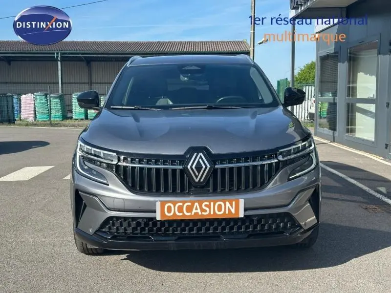 Vue frontale du Renault Espace 2024 gris schiste avec calandre verticale et badge Renault central, en extérieur sur parking.