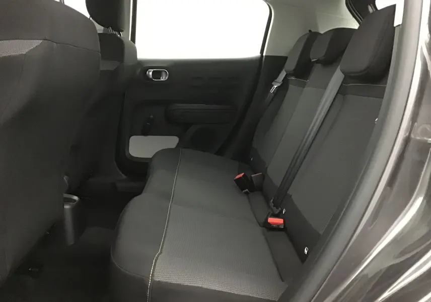 Vue intérieure côté droit des sièges arrière noirs de la Citroën C3 gris platinium 2022, avec ceintures de sécurité visibles.