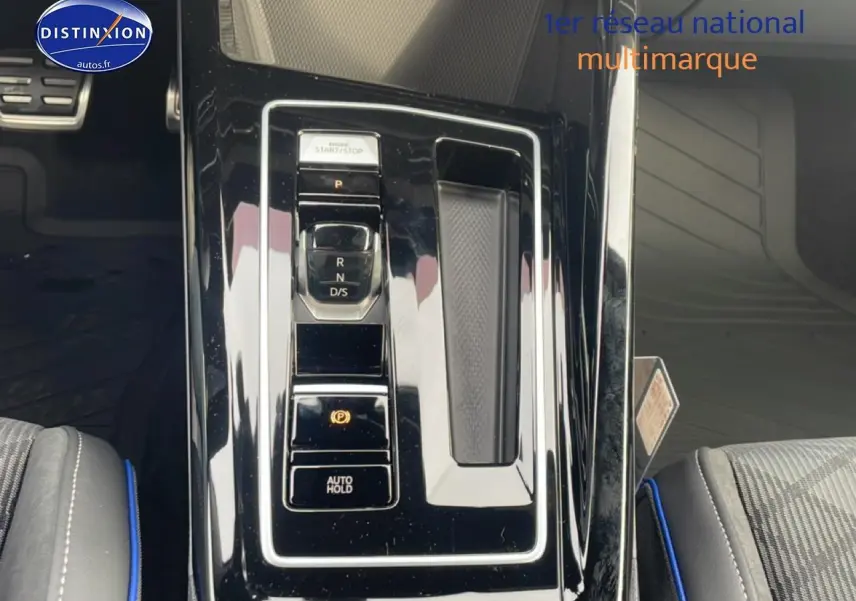 Vue plongeante sur la console centrale noire brillante de la Volkswagen Golf 1.5 eTSI R-Line avec sélecteur de boîte auto.