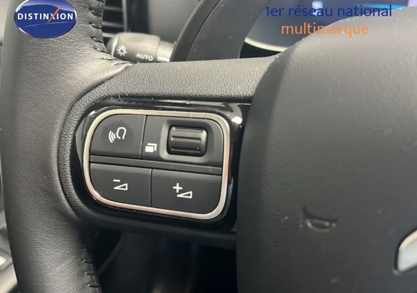 Gros plan sur les commandes gauche du volant noir du Citroën C5 Aircross 2025 hybride, avec boutons de volume et appel.