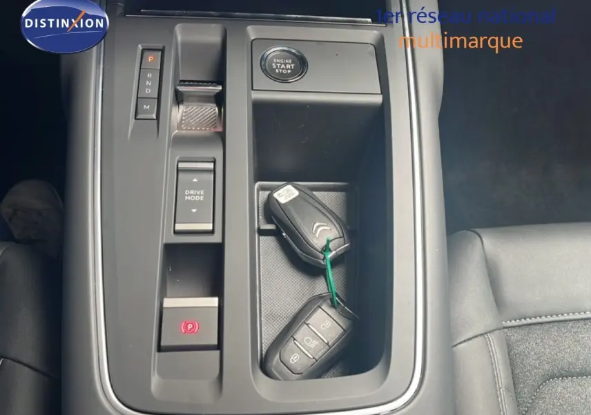 Vue rapprochée de la console centrale noire du Citroën C5 Aircross 2025 avec clés, bouton start et commandes de boîte auto.